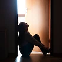 «Sie wollen nicht sterben» Trauriges Teenager-Mädchen sitzt auf dem Boden vor der Zimmertür