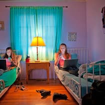 «Onlinesucht kann wirklich alle treffen» Zwei Teenager Schwestern liegen im Bett ihres Schlafzimmers. Beide haben einen Laptop auf ihren Beinen und hantieren gleichzeitig mit einem Smartphone.