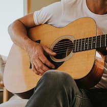 Was im Körper passiert, wenn wir Musik hören oder machen Mann spielt zuhause Gitarre