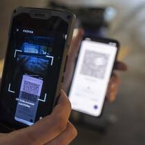 Gefälschtes Covid-Zertifikat – welche Strafe droht? Mann kontrolliert mit Smartphone Covid-Impfzertifikat