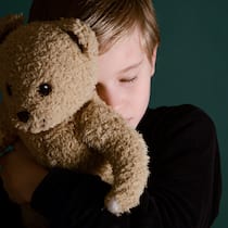 Wie Eltern sich einigen lernen Ein Junge drückt seinen Teddy fest an sich.