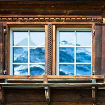Ist die Fensterfirma weg vom Fenster? Bergpanorama spiegelt sich in Fenstern eines alten Hauses