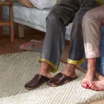 Beinahe getötet – und dann links liegen gelassen Eine Frau und ein Mann sitzen nebeneinander auf einem Bett, man sieht nur ihre Beine, es wirkt friedlich