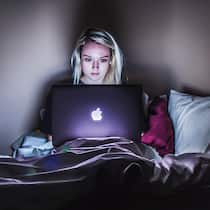 Apple vergibt bald Gratiskredite – das steckt dahinter Frau mit Macbook auf dem Bett