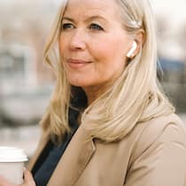 Mit Genuss gegen die Widrigkeiten des Alltags Entspannte Frau wartet an Bushaltestelle