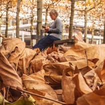 So hoch fällt Ihre 13. AHV-Rente aus Eine Rentnerin sitzt an einem Herbsttag auf einer Parkbank.