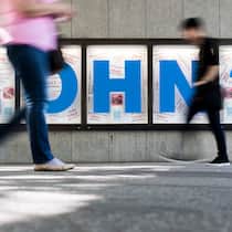 Lohntransparenz bei Firmen unerwünscht – was tun? Menschen gehen vor einem Plakat mit der Aufschrift «Lohn?».