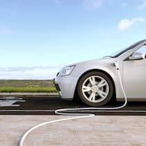 Ladestation vor der Haustür Ein E-Auto steht im Freien auf einem Parkplatz und wird durch ein am Boden verlegtes Ladekabel aufgeladen.