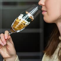 Ein riskanter Cocktail Eine Frau trinkt aus einem Champagnerglas, das mit Medikamenten gefüllt ist.