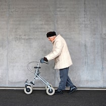 Wer hilft, zusätzliche Kosten zu decken? Alte Frau geht an Rollator
