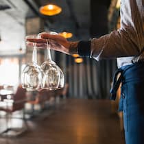 Wer reserviert und nicht erscheint, muss immer öfter zahlen Servicekraft in Restaurant trägt Gläser