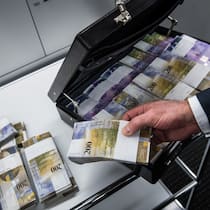 So haben Schweizer Gerichte zu Enteignungen entschieden Ein Mann füllt einen Aktenkoffer mit Tausender- und Zweihundert-Franken-Noten.