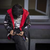 Antifolterkommission bestätigt: Schweiz verletzt Kinderrechte Ein Mann sitzt auf einer Bank und benutzt sein Mobiletelefon, aufgenommen waehrend eines Medienrundgans im Bundesasylzentrum Zuerich, am Donnerstag, 27. Oktober 2022 in Zuerich. (KEYSTONE/Michael Buholzer)