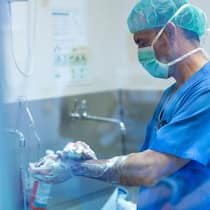 5900 Tote jährlich durch Infektionen im Spital 2E4JEPP Male surgeon in surgical cap using smart phone at hospital