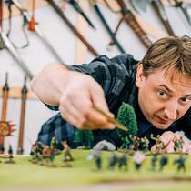 Wo Männer mit Piraten spielen Tabletop-Spieler Simon Künzle denkt über den nächsten Zug nach. Er beugt sich über eine künstliche Landschaft mit Spielfiguren.