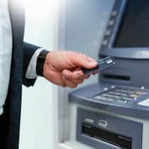 Bankgebühren zu hoch – das können Sie tun Ein Mann hebt Geld am Geldautomaten ab