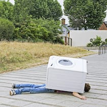 Welche Versicherungen braucht es wirklich? Eine Waschmaschine liegt auf einem Mann.