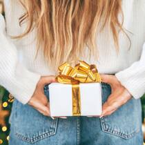 Fünf witzige Wichtel-Varianten, die für mehr Vorfreude sorgen 5 Wichtel-Tipps: Eine Frau hält ein Geschenk hinter dem Rücken