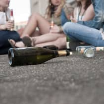 Noch immer Alkohol für Minderjährige Jugendliche mit einer leeren Proseccoflasche auf dem Boden sitzend