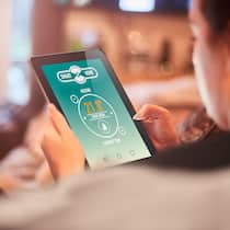 Kontrollieren Sie die Temperatur im Feriendomizil per App Homeowner using Smart home heating technology on the sofa in living room of modern home