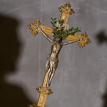 Schweizer Bischof will einen QR-Code für Priester Ein Mann hält am 3. November 2022 in einer dunklen Kirche ein Kruzifix, auf der gegenüberliegenden Wand ist der Schatten des Mannes mit dem Kreuz zu sehen. (Aufnahmeort unbekannt)