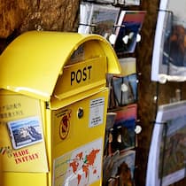 Die Marken-Masche in Bella Italia 2A8HAT4 Civita di Bagnoregio, Lazio, Italy - October 10, 2019: Vintage yellow mailbox for international Mail Service for tourists. Useful for sending postcard