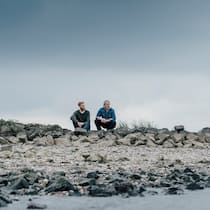 «Nichts tun ist immer falsch» Zwei Männer sitzen an einem Fluss und diskutieren miteinander.