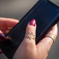 «Der Ton verschärft sich gegen alle Minderheiten» Frau mit Davidstern-Ring an der Hand hält Smartphone