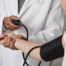 Lautlose Gefahr Ein Arzt misst den Blutdruck einer Frau.