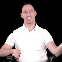 Er will Leute mit Handicap stärken Prix Courage 2021 Kandidat Islam Alijaj sitzt im weissen T-Shirt vor einem schwarzen Hintergrund.