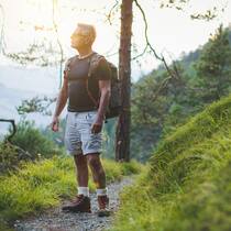 Wie die Sinne die Selbstheilung unterstützen Ein Mann blickt auf einer Wanderung nachdenklich in die Landschaft