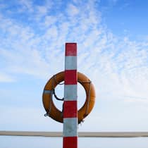 Wer zahlt die Annullierungskosten? Bild eines Rettungsrings am Strand.