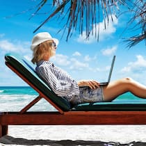 So finden Sie das beste Angebot Frau liegt mit Laptop in der Hand auf einem Liegestuhl am Strand unter Palmen