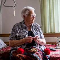 Was tun bei steigenden Pflegekosten? Eine Seniorin strickt in ihrem Zimmer im Altersheim.