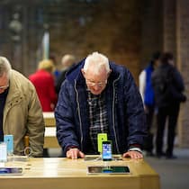 Hilfe bei der Handybedienung Zwei Senioren schauen sich Smartphones in der Auslage an