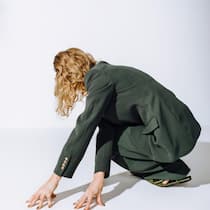 Frau Berger erkämpft sich das Leben zurück – dann geht sie shoppen Back view of unrecognizable female fashion model in green suit and pants leaning on floor on white background