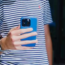 So unterstützen Sie Ihr Kind auf Social Media Ein Jugendlicher hält ein Smartphone vor seiner Brust.
