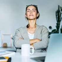 Langsam atmen – schnell entspannen Entspannte Frau am Arbeitsplatz