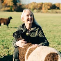 Ist es sinnvoll, eine Auszeit zu nehmen? Eine Frau mittleren Alters hält ein Schaf im Arm.