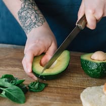 Glykämischer Index Eine Frau schneidet eine Avocado auf.