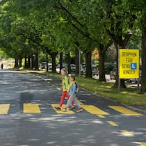 Autofahrer müssen Rücksichtnahme lernen Kinder, die einen Fussgängerstreifen überqueren. Im Hintergrund die Plakatkampagne, die zu mehr Rücksicht aufruft.