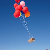 Bestellt in der Schweiz – geliefert von irgendwoher Ein Paket schwebt an bunten Ballons durch die Luft.