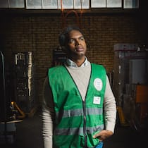 «Wer stundenlang ansteht, hat offensichtlich Hunger» Amine Diare Conde steht in einer Lagerhalle, er blickt seitlich nach oben und trägt eine grüne Arbeitsweste.