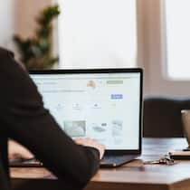 Betrüger kapern Benutzerkonten Mann schaut am Tisch auf Laptop die Website von anibis.ch an