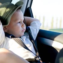 Das gilt, wenn Kinder im Auto mitfahren Ein kleiner Junge sitzt im Auto in einer Kinderrückhaltevorrichtung.
