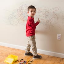 Wer zahlt Schäden in der Mietwohnung? Ein kleiner Junge wird dabei ertappt, wie er an die Wand des Wohnzimmers zeichnet.