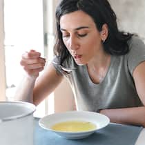 Das sollten Sie essen, um schneller gesund zu werden Eine Frau mit Grippe isst eine Suppe. Bei Erkältung und Grippe hilft es, die Ernährung ein wenig anzupassen.