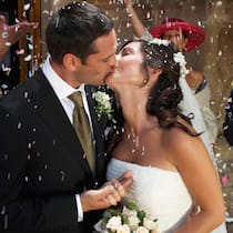 Lohnt es sich zu heiraten? Ein frisch vermähltes Paar küsst sich an seiner Hochzeitsfeier.