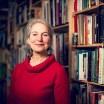 «Essen ist eine gesamtkörperliche Erfahrung» Die Ernährungswissenschaftlerin Christine Brombach trägt einen roten Pullover, steht vor einer Bücherwand und lächelt.