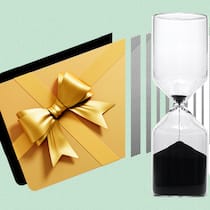 Warum du Gutscheine nicht in der Schublade vergessen solltest Eine Geschenkkarte neben einer Sanduhr vor grünem Hintergrund. Wann Geschenkbons ihre Gültigkeit verlieren.